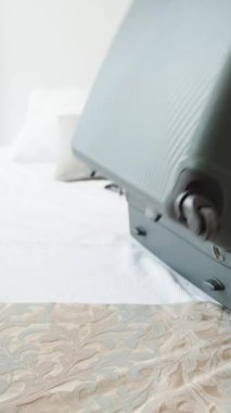 Genç kadın eşyalarını bir bavula koyup yatağa koyar. Güneşli bir gün. Bavulu dikey video ile kapatır.