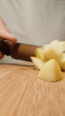 Genç kadın ayva küplerini kesiyor, çok zor ve masa sallanıyor, yakın plan. Dikey video Sosyal Ortamı
