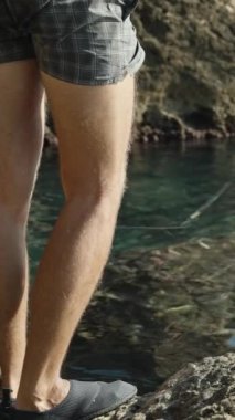 Şortlu bir adam turkuaz deniz suyunda balık tutuyor. Etrafı sallıyor. Dikey video Sosyal Ortamı