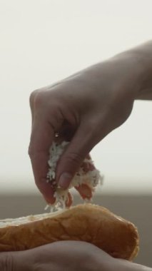 Sahilde sosisli pişiririz. Üzerine rendelenmiş peynirli çörek serpin. Dikey video Sosyal Ortamı