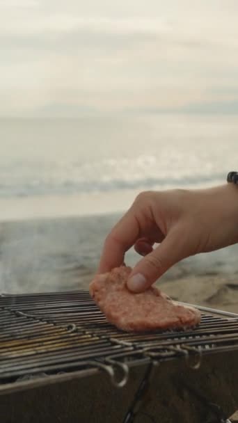 海のピクニック 私はグリルに2つのハンバーガーパティを置きました クローズアップ 垂直ビデオ ソーシャルメディア — ストック動画