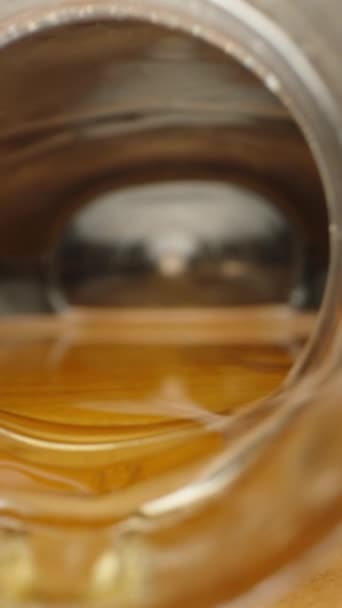 摄像机移出瓶子 蜂蜜从罐子流到桌子上 坚果散落在桌子上 非常接近的垂直视频社交媒体 — 图库视频影像