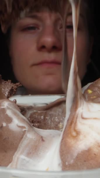 一个年轻的女人用勺子在杯子里吃着冰激凌 这是特写镜头 在一个黑色的背景 垂直视频社交媒体 — 图库视频影像