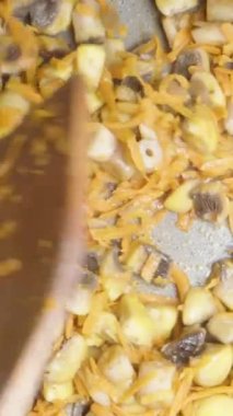 Mantarları ve havuçları tahta bir spatulayla kızartma tavasında karıştır. Yukarıdan yakından bak. Dikey video Sosyal Ortamı