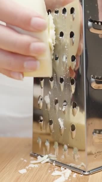 女孩在金属研磨机上擦奶酪 相机在一个圆圈中移动 慢动作垂直视频社交媒体 — 图库视频影像
