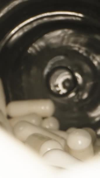 白色胶囊形式的薄片在一个黑色的罐子里旋转着 摄像头在里面 多莉滑行极端特写 垂直视频社交媒体 — 图库视频影像