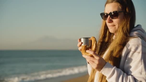 Młoda Kobieta Kapturze Nad Morzem Bajgla Pije Gorącego Drinka Termosu — Wideo stockowe