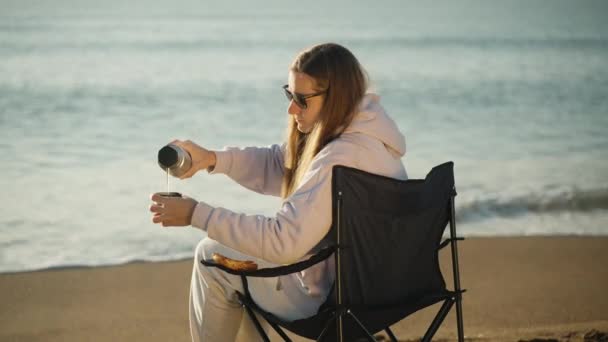 Młoda Kobieta Krześle Nad Morzem Nalewa Gorącą Herbatę Termosu Wschód — Wideo stockowe
