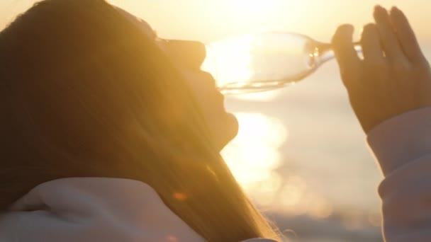 在太阳升起的背景下 一个年轻的女人喝着香槟酒 喝到最后一滴 动作缓慢 — 图库视频影像