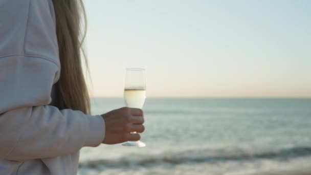 在清凉的清晨 一位年轻女子带着一杯香槟沿着海滨散步 — 图库视频影像