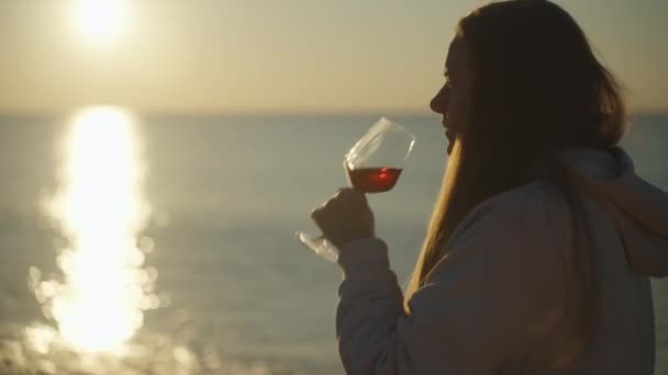太阳升起在海面上 阳光闪耀在水面上 一位年轻女子喝着杯子里的酒 — 图库视频影像