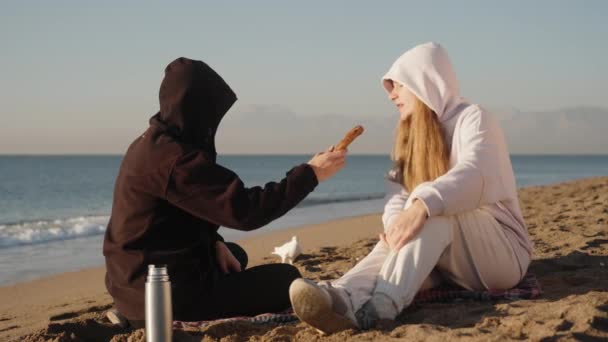 男は若い女性にバゲルを渡して噛ませ それから白い鳩に餌を与えた 海岸の日付について — ストック動画