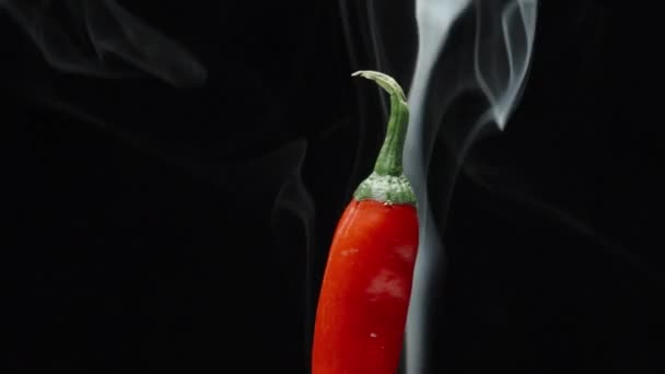 一半的红辣椒在黑色背景下旋转和吸烟 — 图库视频影像