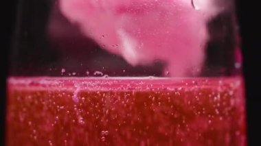 Bir kadeh şampanyaya pembe pamuk şeker atıyorum, tatlı bir kokteyl, yakın plan..