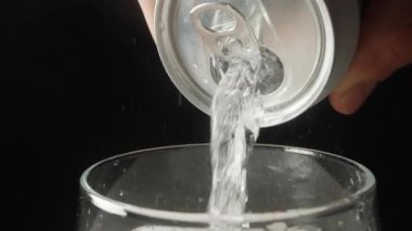 Sahne yavaşça dönüyor ve soda yavaşça siyah arka plandaki bir kutudan dökülüyor, yakın plan..
