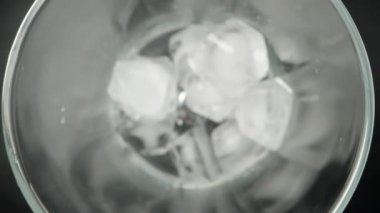 Buz küpleri bir bardağa düşüyor, üst görünüm siyah arka plan, yavaş çekim, makro