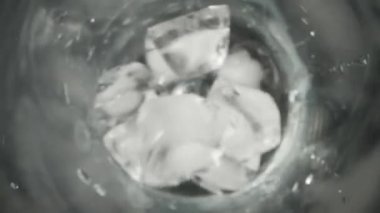 Buz küpleri bir bardağa düşüyor, üst görünüm siyah arka planda, yavaş çekim, makro Kaydırıcı