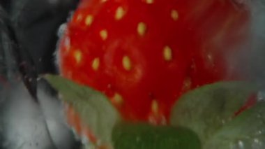 Kamera, içinde çilek olan bir bardak soda ve buzdan yükselir. Makro kaydırıcı.