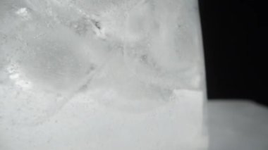 Soda bardağındaki buz küpleri ve kabarcıklar yükseliyor, siyah arka planda makro..