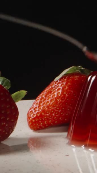 红果冻和草莓在盘子里 我用勺子敲它 它抽搐着 垂直视频社交媒体 — 图库视频影像
