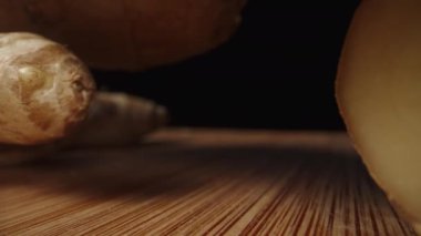 Bambu masasının üzerinde zencefil kökleri üst üste yatar ve parçalara ayrılır. Dolly sürgülü çok yakın çekim..