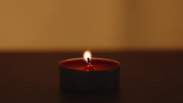 我在一张木制桌子上吹灭了一个红色的圆形蜡烛 背景中闪烁着光芒 — 图库视频影像