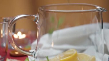 Cam çaydanlığa nane yaprağı koydum, arka planda bir mum yanıyor. Yakın plan.