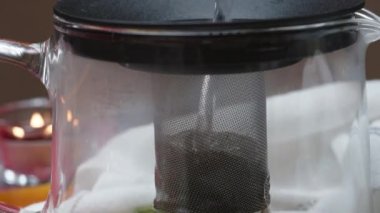 Bir çaydanlığa elek içinde kaynar su dökerim. Limonlu ve naneli çay. Yakın çekim, yavaş çekim