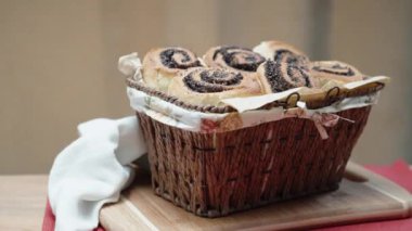 Slaytlı hasır sepetin içinde haşhaş tohumları, ahşap bir masa örtüsü ve kırmızı bir masa örtüsü bulunur.