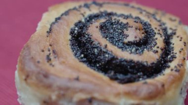 Haşhaş tohumlu bir çörek kırmızı masa örtüsü üzerinde döner.