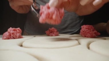 Hamur köfteleri için kıyma parçalarını hamurun üzerine yaydım. Dolly kaydırıcı aşırı yakın çekim.