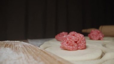 Ev yapımı hamur köfteleri için hazırlıklar, kıyma parçaları hamurun üzerine konur. Tahtadaki hamur köfteleri. Dolly kaydırıcı aşırı yakın çekim.