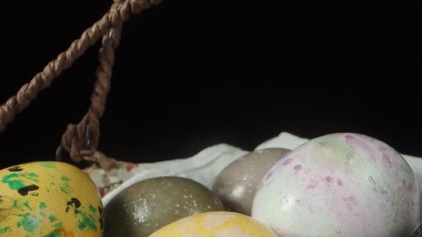 復活祭の卵を飾るハンドルを持つウィッカーバスケット 黒の背景に隔離された ドリースライダー極端なクローズアップ — ストック動画