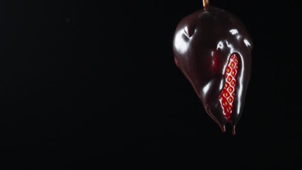 少女はチョコレートで覆われたイチゴに手を伸ばし 噛み付こうとする ブラックバックのクローズアップ — ストック動画