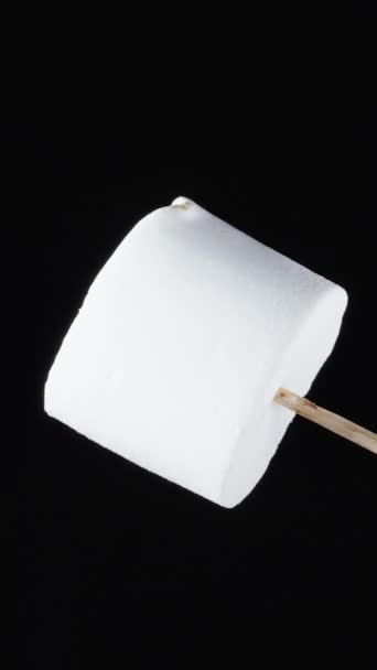 마시멜로우는 막대기와 갈색으로 회전하여 카라멜 클로즈업 배경에 고립된 물체를 만듭니다 — 비디오
