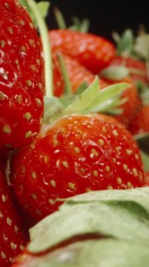 Islak ve sulu çilek dağları. Siyah bir arka planda. Dolly Slider aşırı yakın çekim. Dikey video Sosyal Ortamı