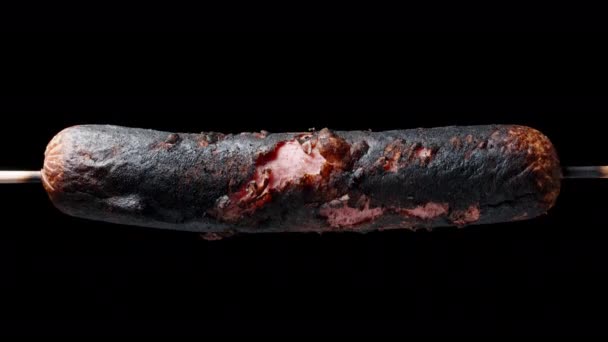 Spalona Kiełbasa Skorupą Rozerwaną Kawałki Obraca Się Czarnym Tle Zbliżenie — Wideo stockowe