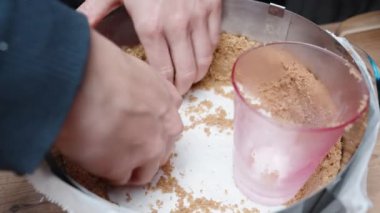 Pasta şefi peynirli kek için küfün duvarlarını ezilmiş kurabiyelerle kaplıyor..