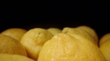 Limonlar masanın üzerine dizilmiştir. Siyah bir arka planda. Dolly kaydırıcı aşırı yakın çekim.