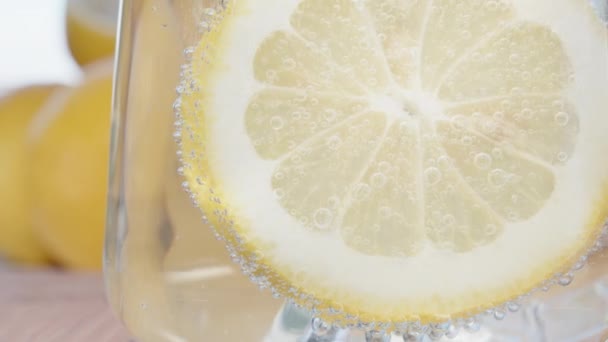一杯苏打水和泡泡里的一片柠檬 滑翔机 柠檬放在桌子后面 — 图库视频影像