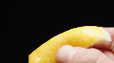 Limon kabuğunu sıkıyorum ve her yöne su sıçratıyorum. Yavaş çekim siyah arkaplan.