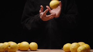 Limonlar siyahlı adama atılır ve o da onları masaya koyar. Yavaş çekim.