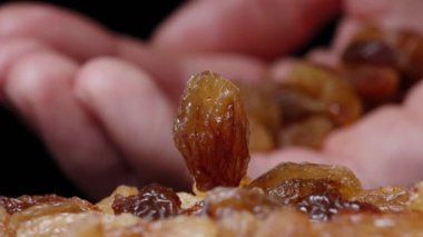 Kuru üzümler masada dönerken avucuma bir avuç kuru üzüm döküyorum. Yavaş çekim.