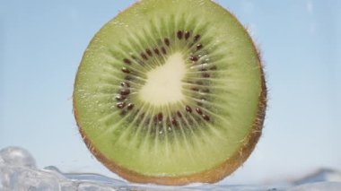 Soda yavaşça mavi gökyüzünün arka planında Kiwi olan bir bardağa dökülüyor, makro..