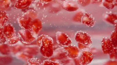 Kırmızı nar tohumları soda içinde kabarcıklar halinde döner. Yavaş çekim yakın çekim