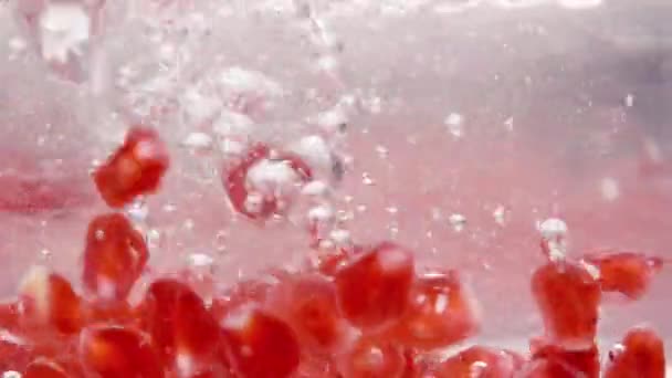 Granatapfelkerne Fallen Ins Wasser Und Steigen Mit Luftblasen Auf Makro — Stockvideo
