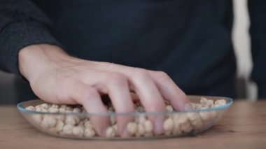 Adam eline bir avuç nohut aldı ve tabağa geri döktü. Yavaş çekim.