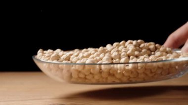 Şeffaf bir tabak dolusu nohut ahşap bir masaya konur..