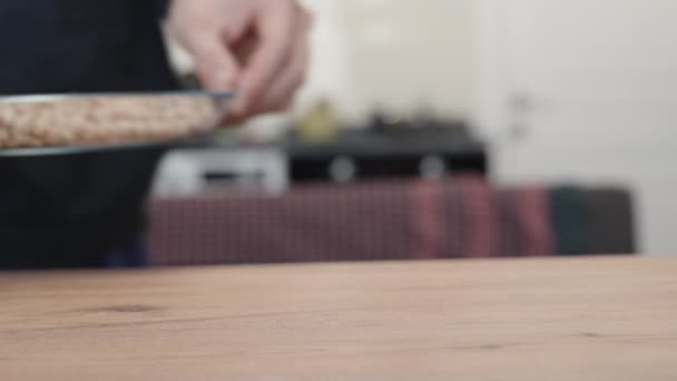 厨房里的一个人把一盘鹰嘴豆放在一张木桌上 — 图库视频影像