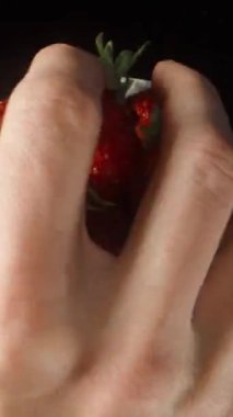 Çilekler tabakta döner. Bir avuç dolusu alıyorum ve kameraya getiriyorum. Macro, hızlandırılmış çekim. Dikey video Sosyal Ortamı